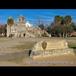 The NPS Entrance sign for Mission Conception Area of San Antonio Missions with the Church behind it.